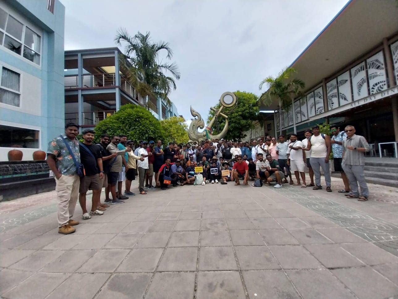 Large tour group posing together in a Phuket hotel courtyard beside a decorative anchor