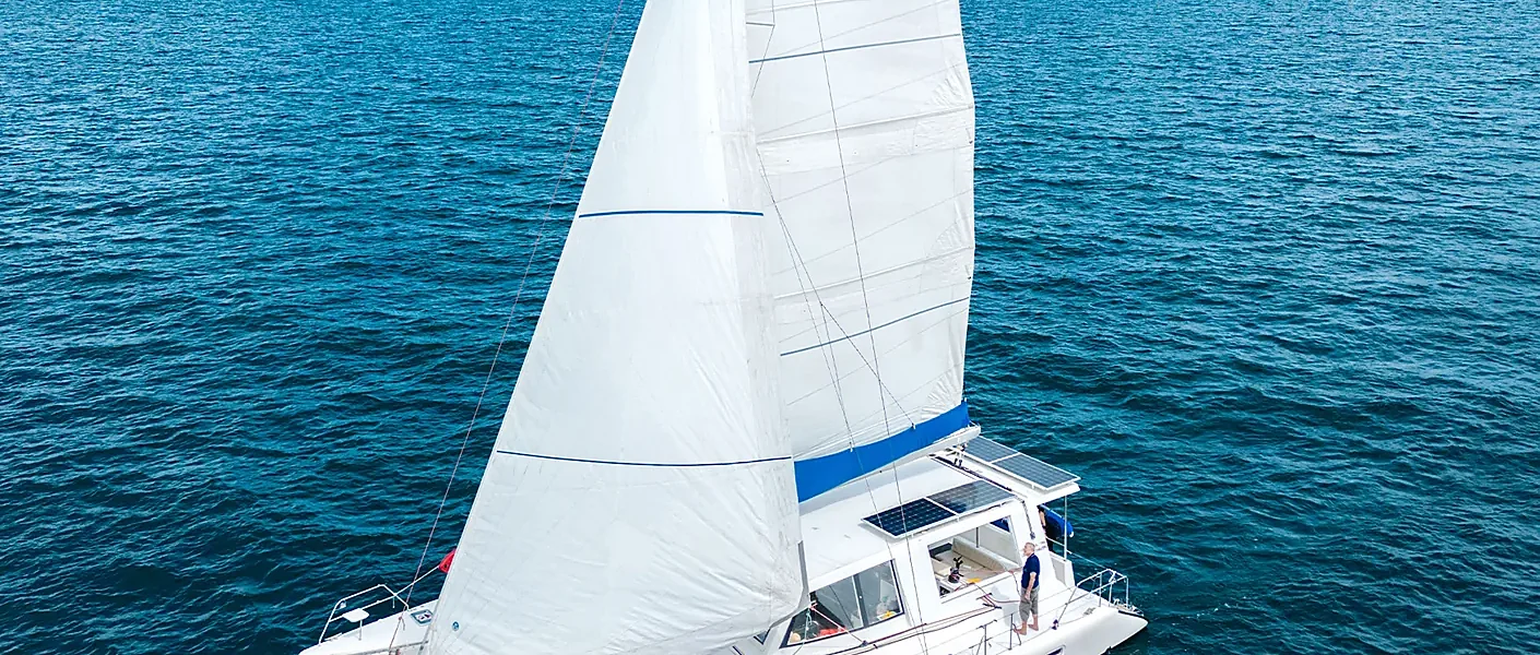 Sailing catamaran anchored near turquoise waters off Coral Island and Racha Island, Phuket, at golden sunset