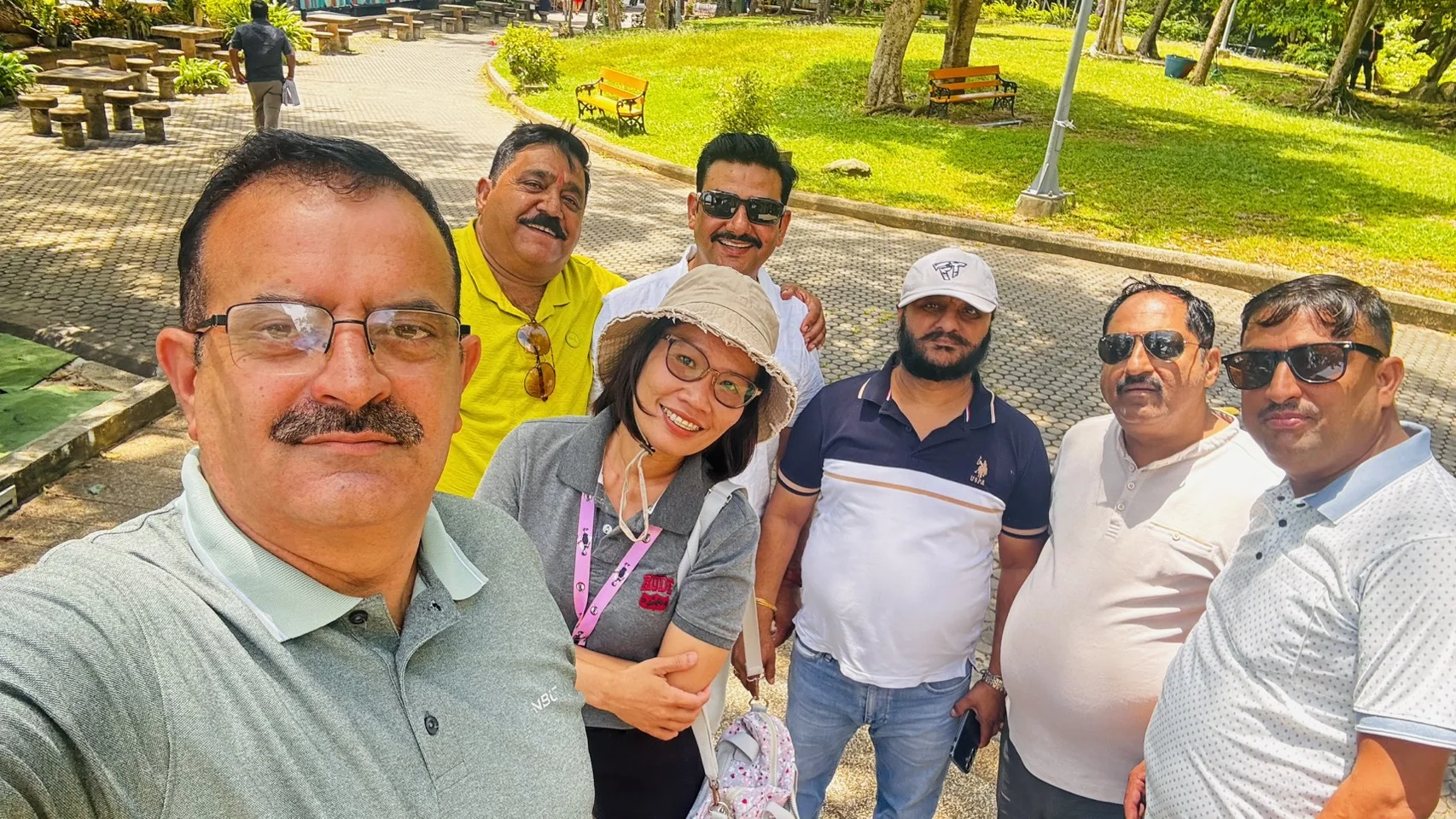 Group of travelers and a tour guide taking a selfie in a sunny Phuket garden