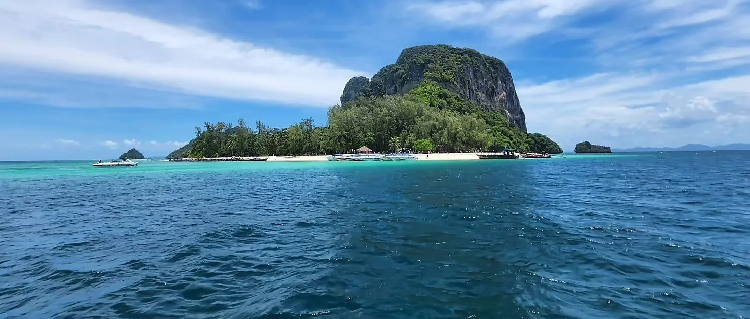 Speed boat gliding past dramatic limestone cliffs on a 4 Island Tour in Krabi, Thailand