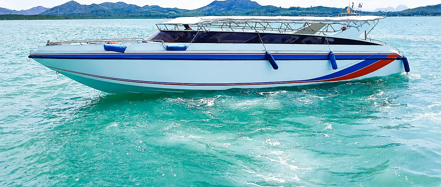Speed boat cutting through turquoise waters near Koh Yao Yai with a taxi waiting on the pier for hotel transfers