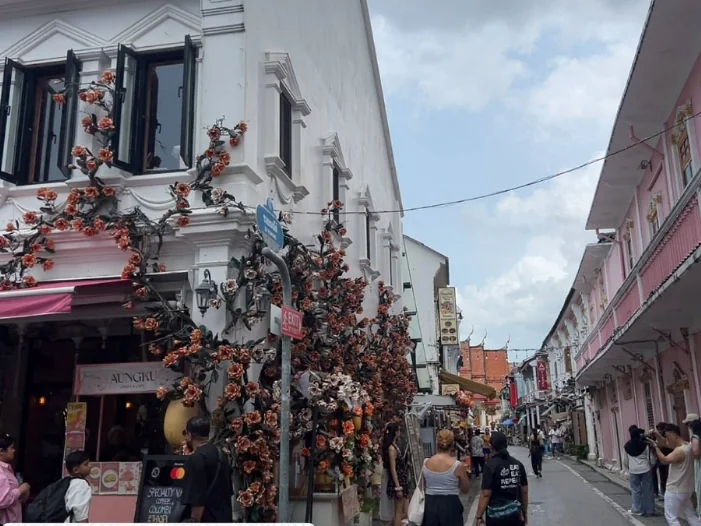 Flower-covered cafe and colorful Sino-Portuguese buildings on a busy street in Phuket Old Town