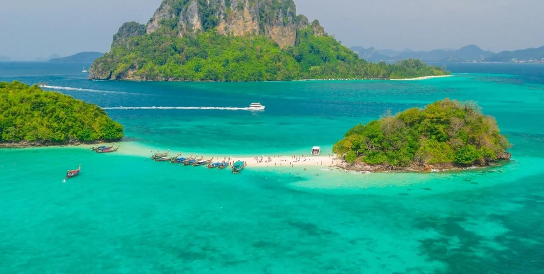 Long-tail boat gliding past limestone karsts on the Krabi 4 Island Tour in turquoise Andaman waters