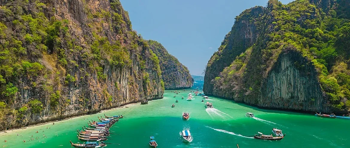 Turquoise waters and dramatic limestone cliffs surrounding Phi Phi Island on a sunny day