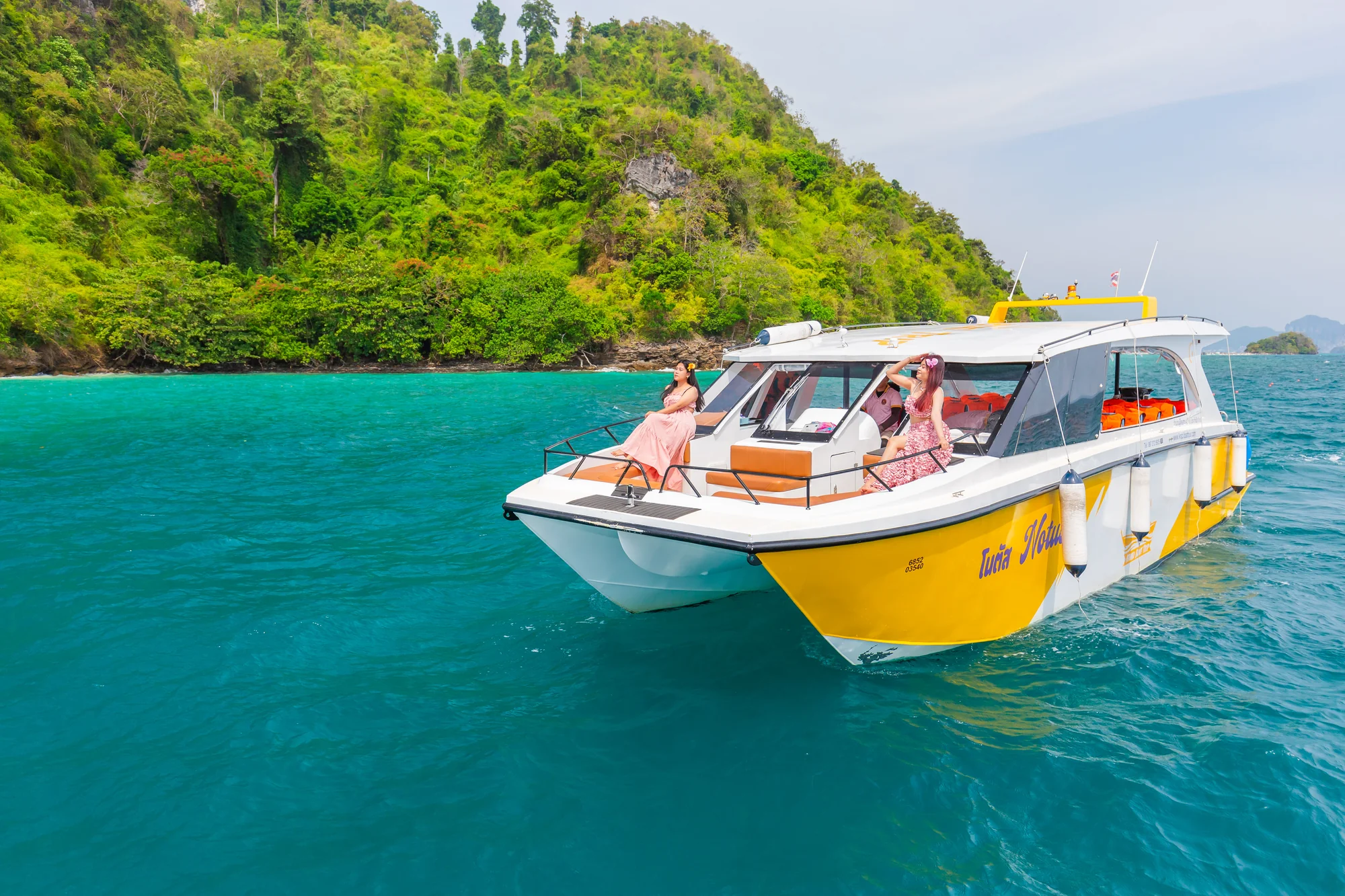 Catamaran sailing past Phi Phi Island's dramatic limestone cliffs on a sunny day