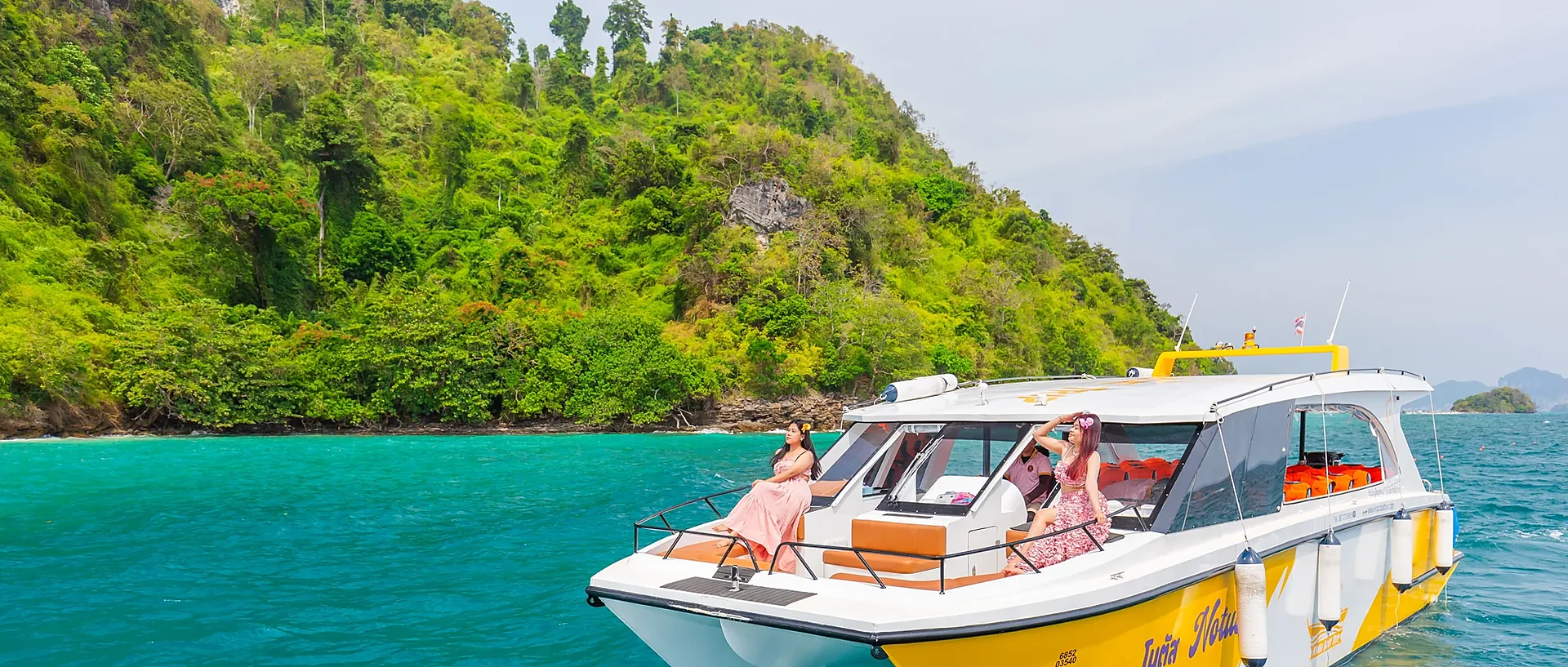 Catamaran sailing past Phi Phi Island's dramatic limestone cliffs on a sunny day