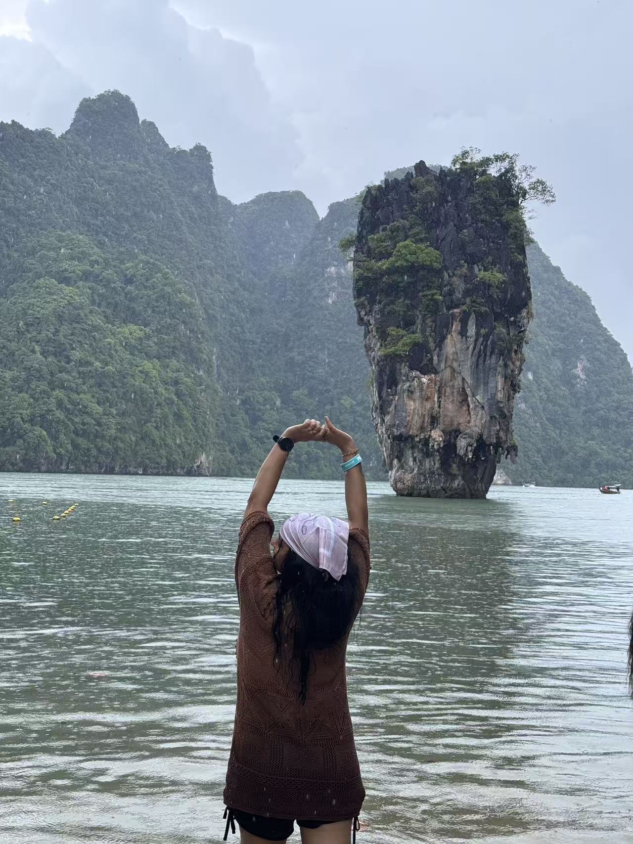 Traveler admiring Ko Tapu limestone rock in the rain at James Bond Island, Phang Nga Bay