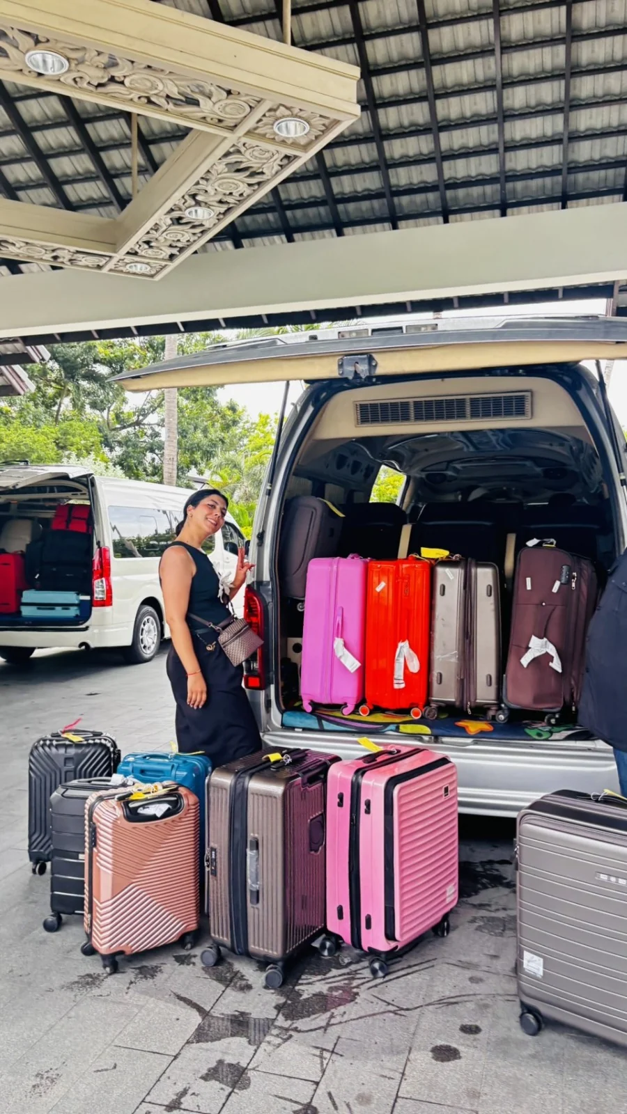 Traveler beside a Phuket transfer van loaded with colorful suitcases at a hotel entrance