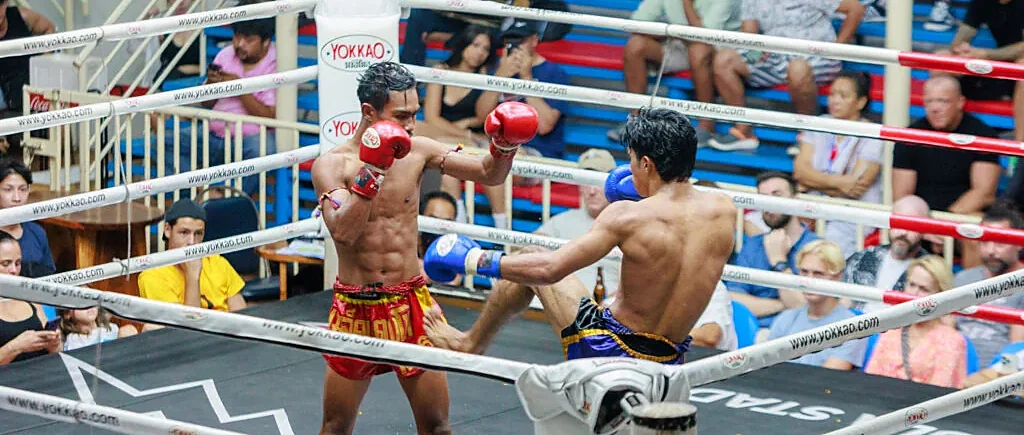 Two Muay Thai fighters compete in the ring at Patong Boxing Stadium, Phuket, as a crowd watches intently