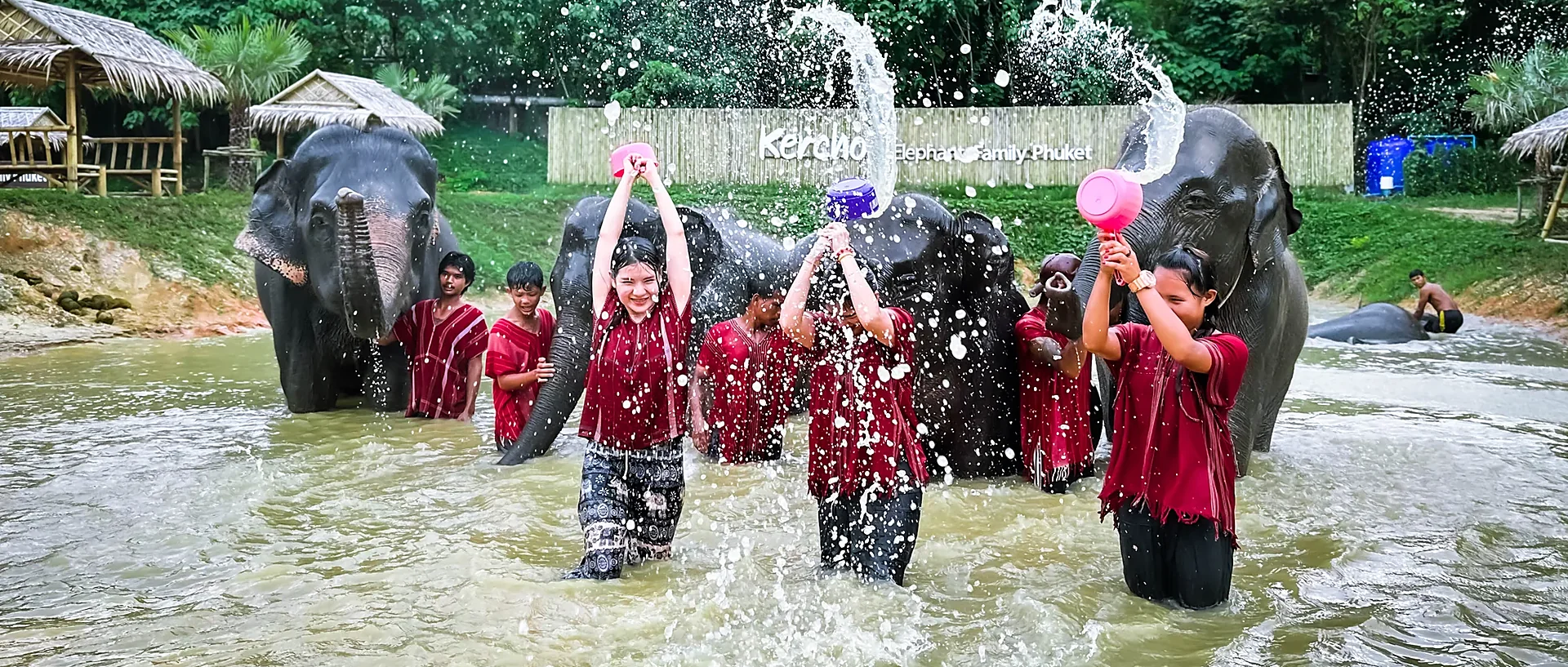 Tourists feeding and showering elephants at a Phuket elephant camp during a morning tour
