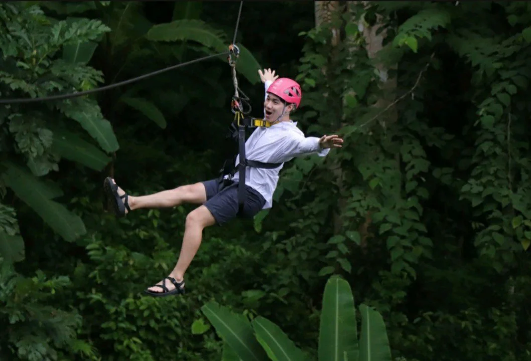 Traveler ziplining through lush rainforest at Hanuman World adventure park in Phuket