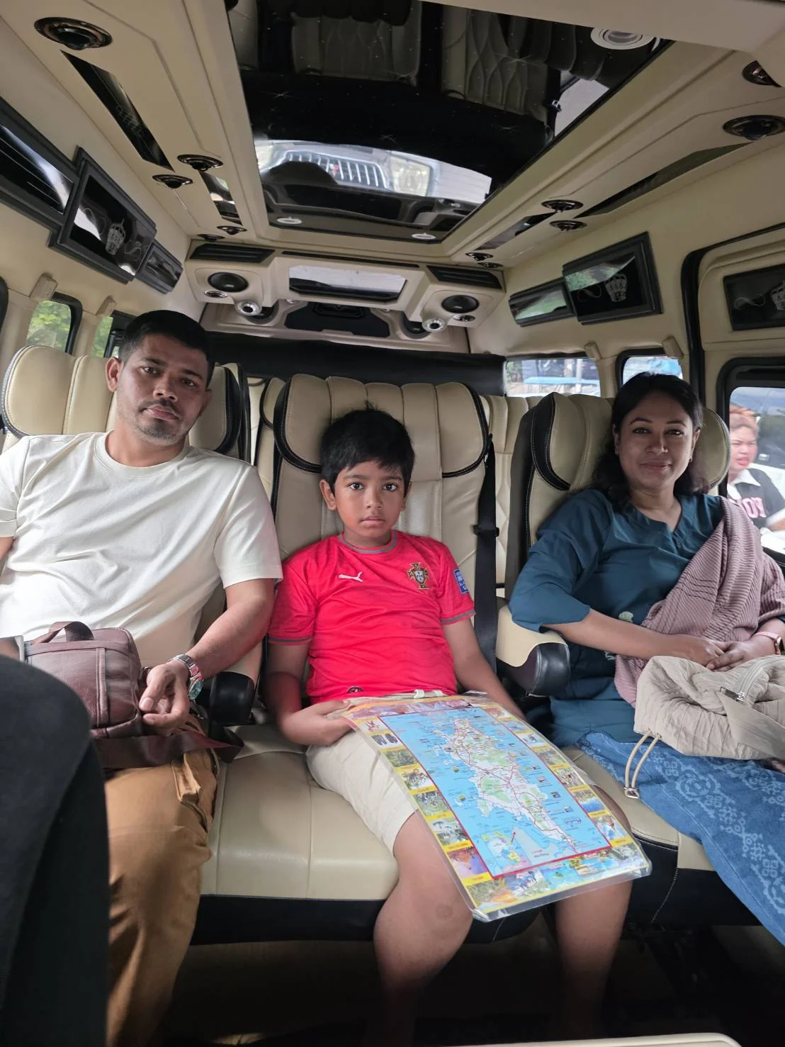 Three guests seated in a luxury private tour van with a Phuket map