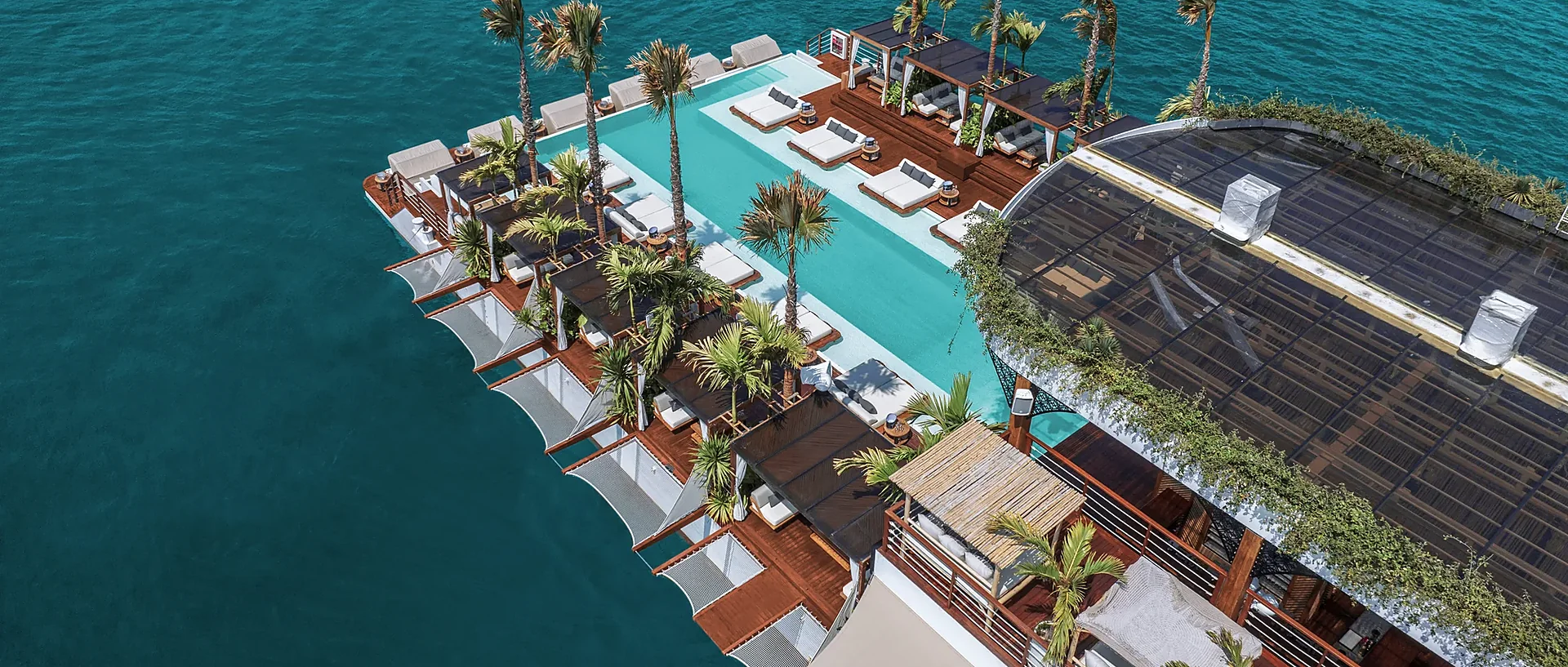 Aerial view of YONA beach club in Phuket with turquoise pools and ocean backdrop on a sunny morning