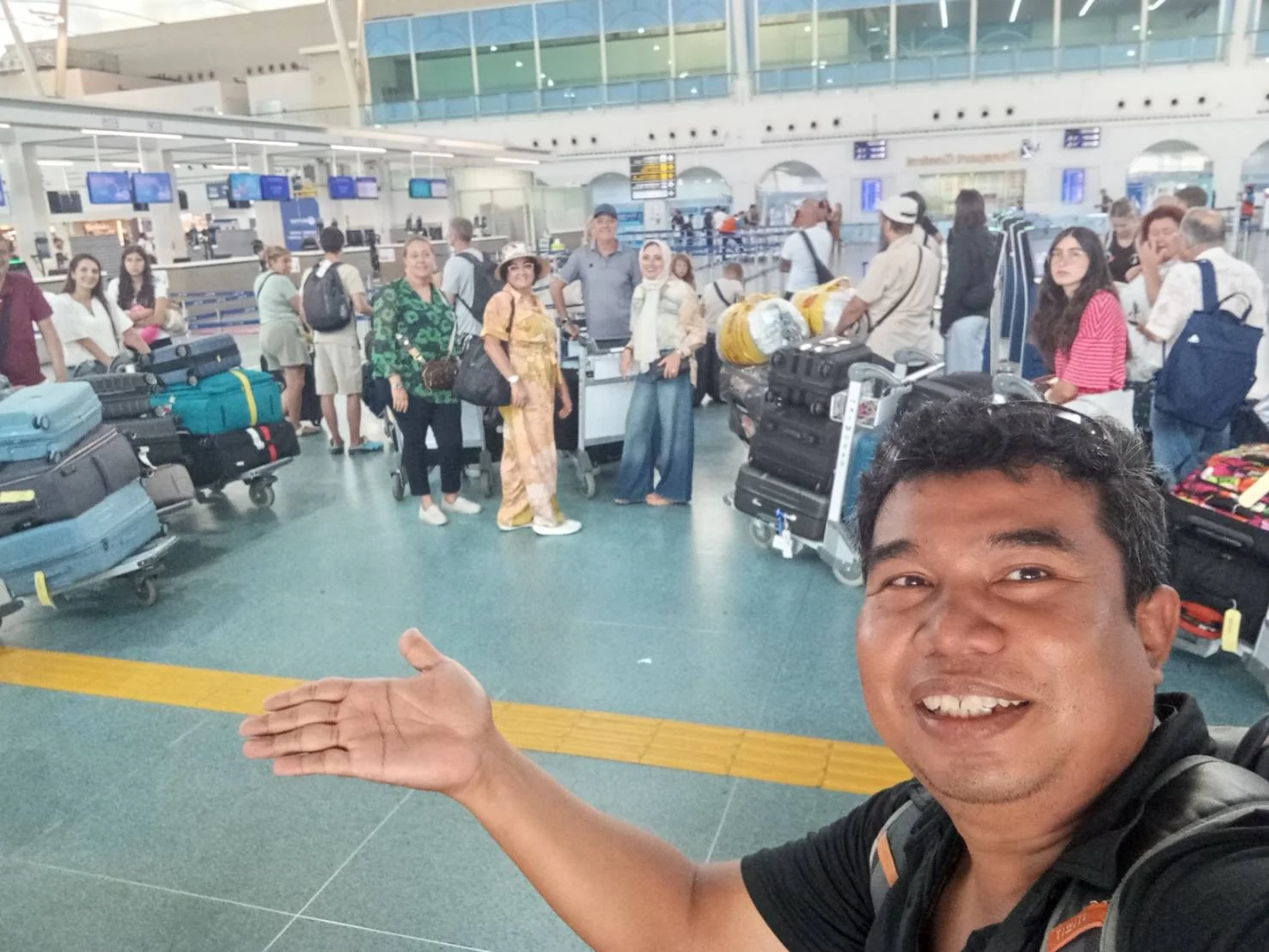 Airport staff selfie with arriving guests and luggage carts inside Phuket International Airport terminal