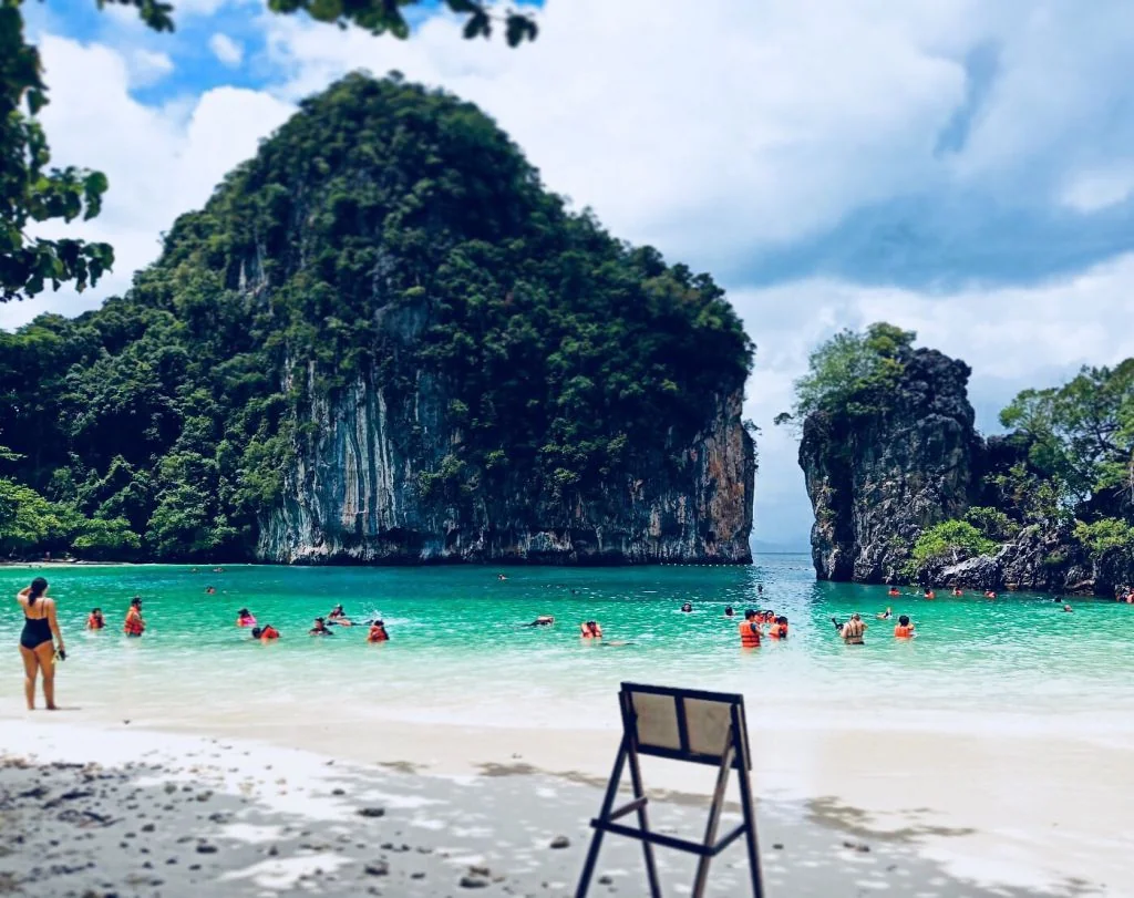Speed boat anchored near Hong Island's turquoise lagoon surrounded by towering limestone cliffs, Krabi