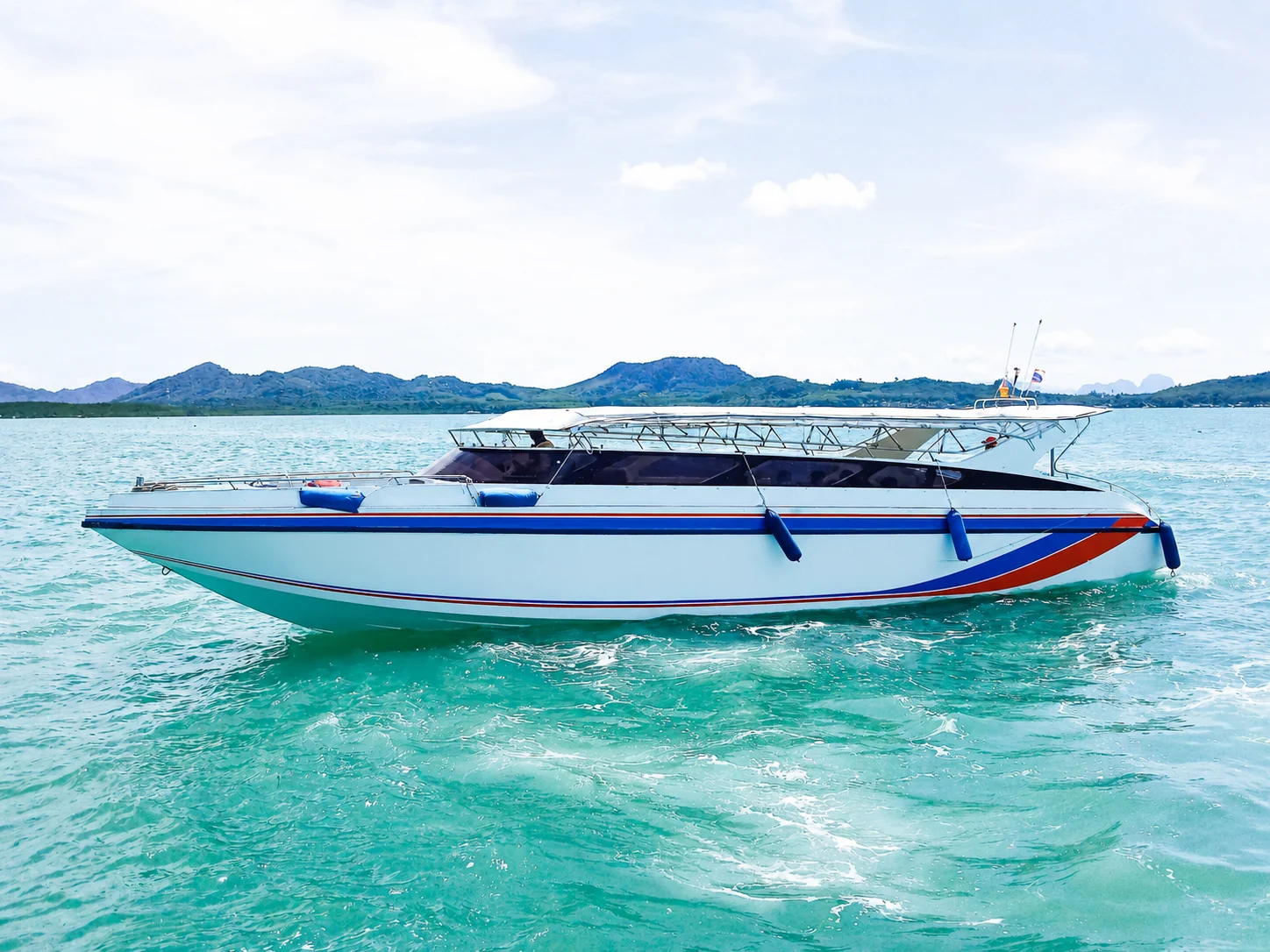 Speed boat cutting through turquoise waters between Koh Yao Yai and Phuket on a sunny day