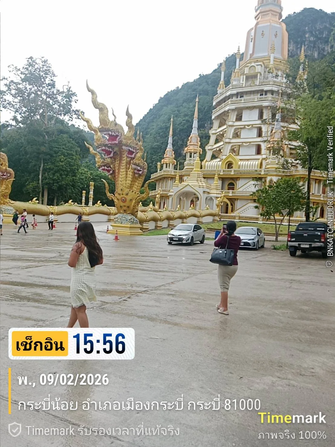 Visitors exploring the ornate temple and golden Naga statue at Tiger Cave Temple, Krabi