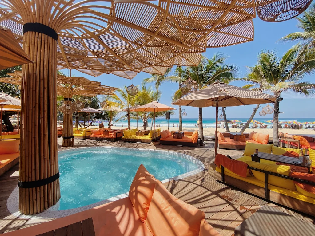 Tann Beach Club's stylish sunbeds and ocean views at sunset on Karon Beach, Phuket