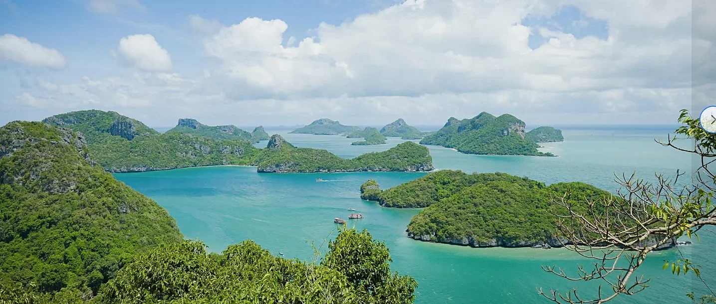 Tour boat sailing through Angthong National Marine Park's emerald islands and limestone cliffs near Samui