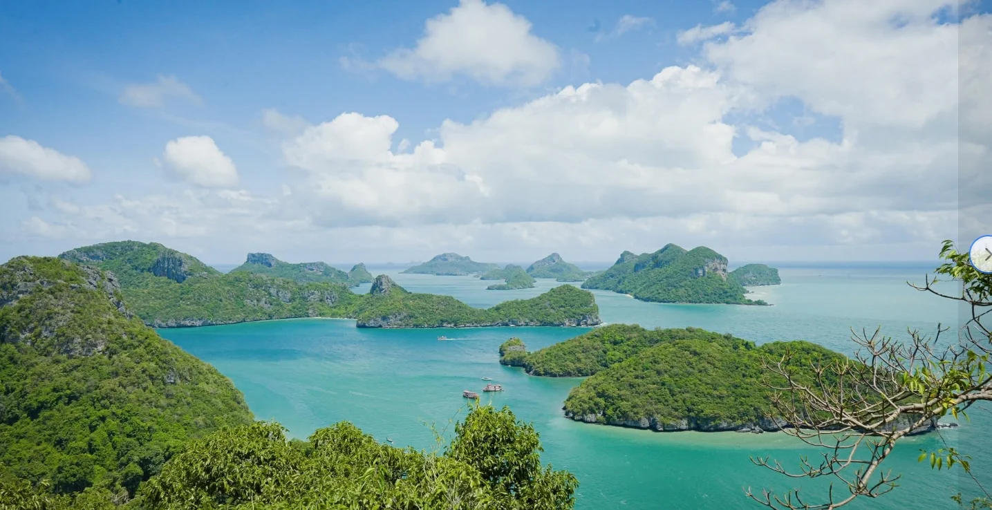 Tour boat sailing through Angthong National Marine Park's emerald islands and limestone cliffs near Samui